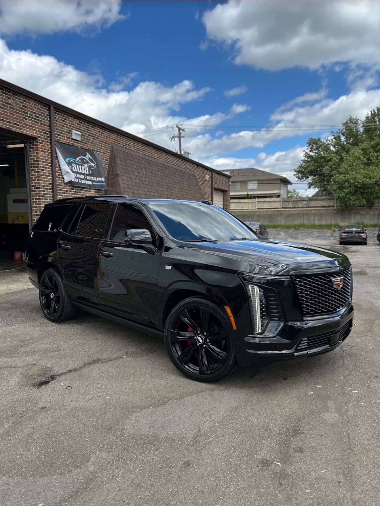 Freshly detailed black Cadillac Escalade outside Aura Spa Car Wash